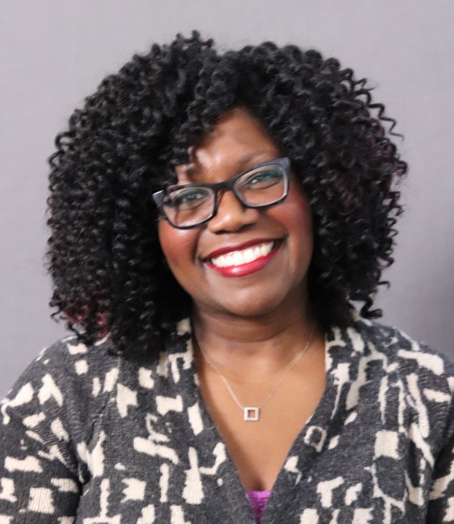 Photo of the Dean for the Class of 2025: a smiling woman in a black and white-patterned sweater.